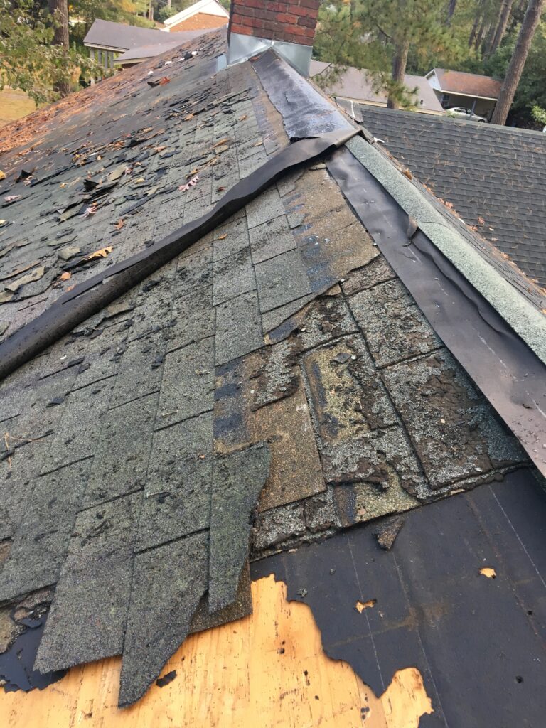 A roof in poor condition with damaged and missing shingles