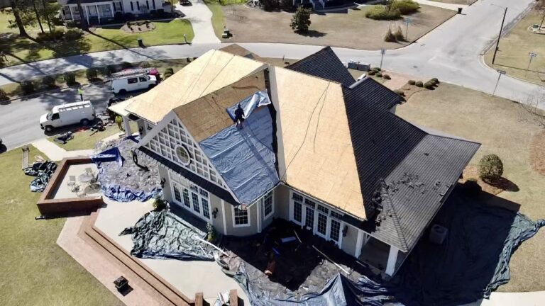 roofers repairing the decking of a large home with gables to install new roofing materials
