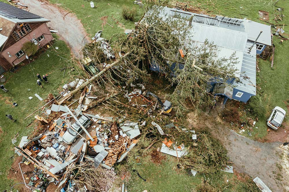 Aerial photo of a house damaged in a storm with trees on a part of the roof