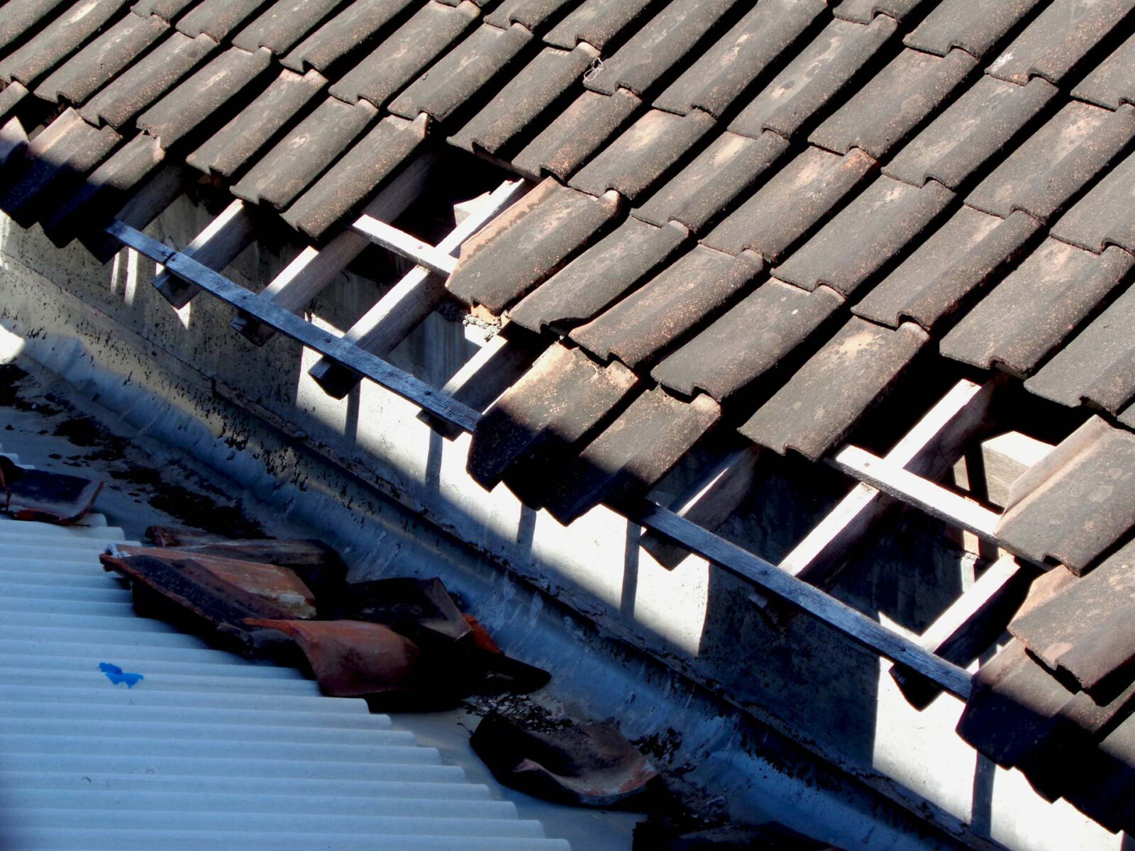An old roof with lifted and blown-off tiles due to strong winds