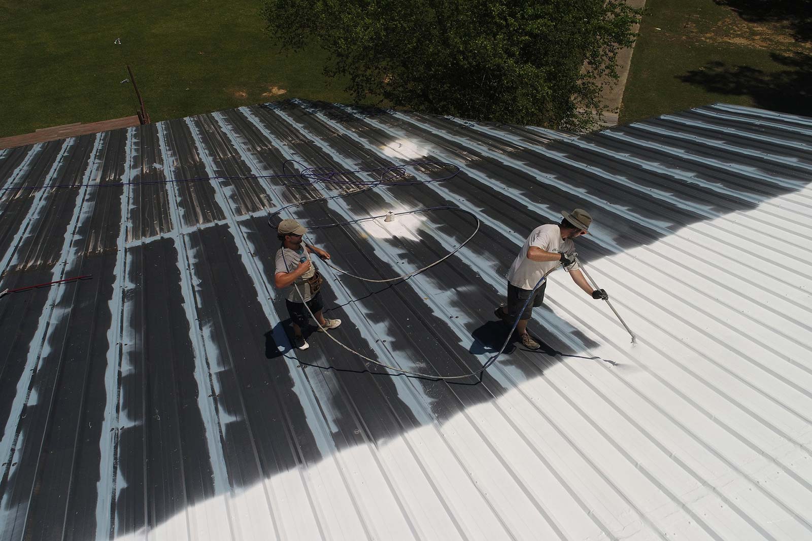 men applying roof coating on a metal commercial roof