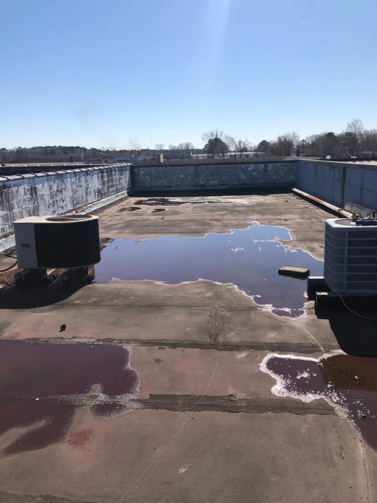 A damaged flat roof with pooling water