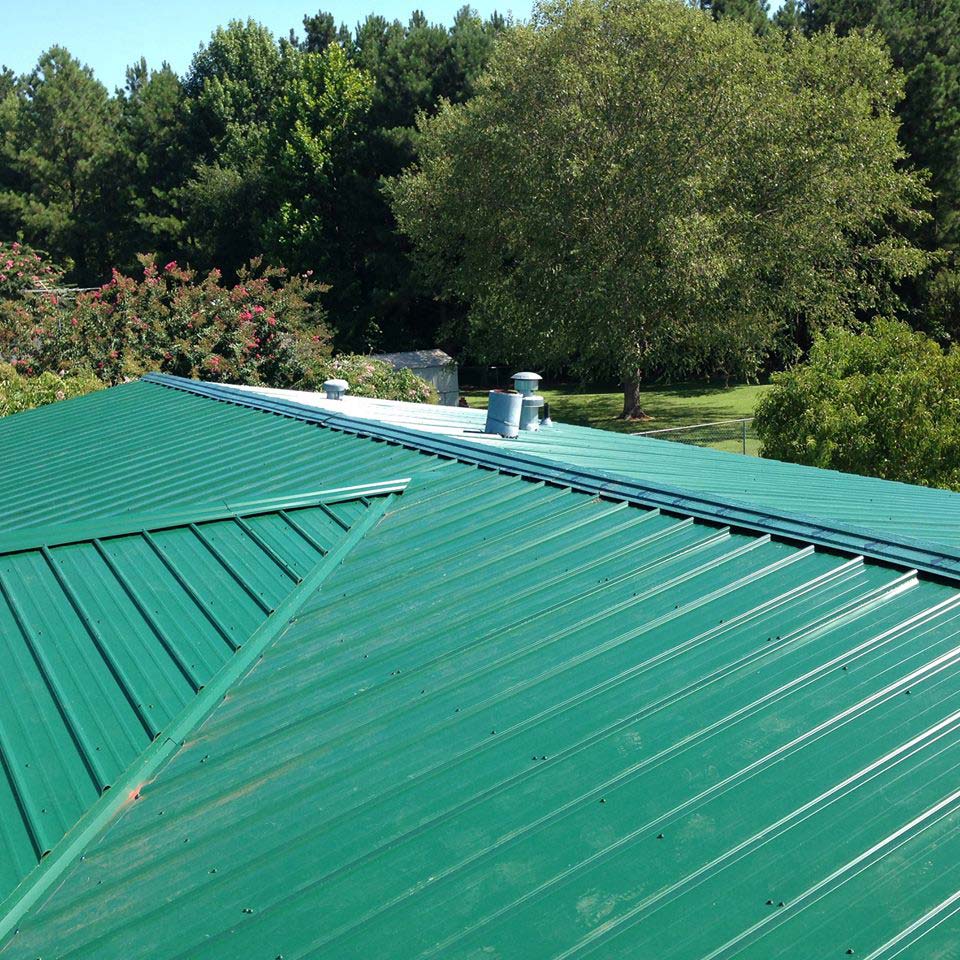 Green metal roof against a background of trees