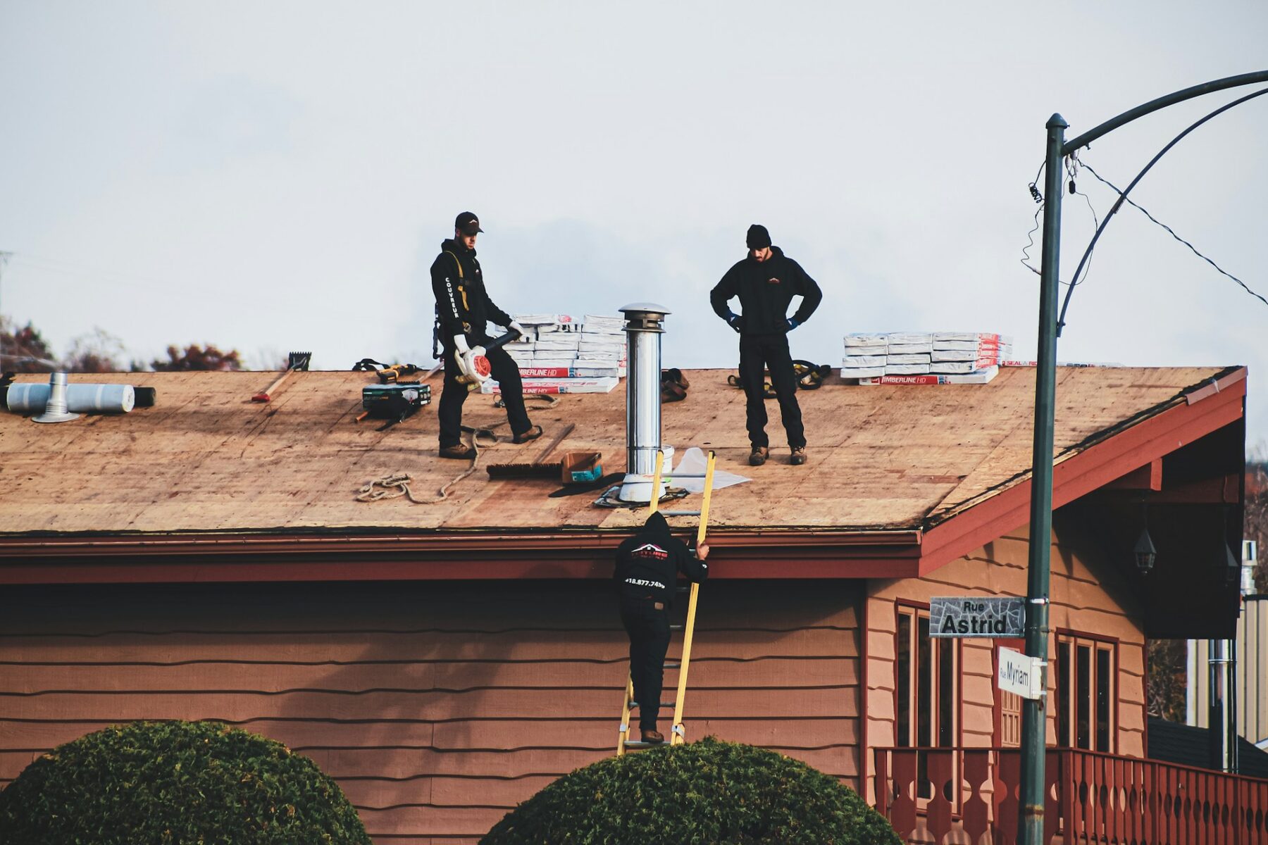 Roofers standing on a newly installed asphalt shingle roof