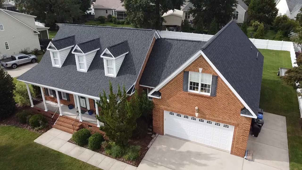 A brick house with a white garage door and a new shingle roof